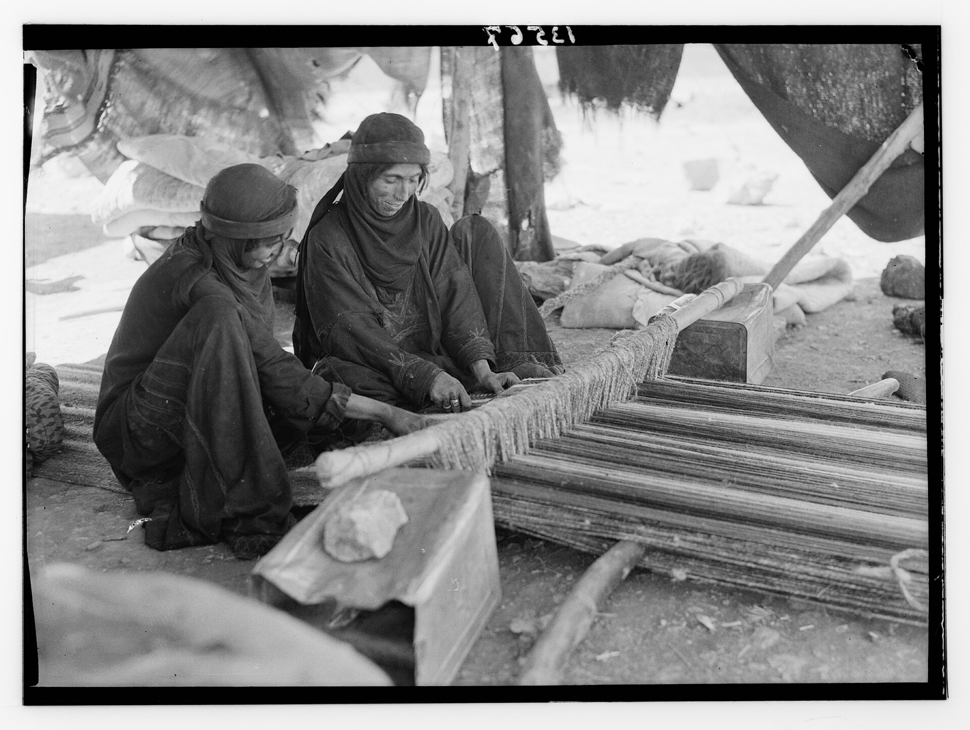 Archival photograph of two Bedouin women weaving together on a horizontal ground loom